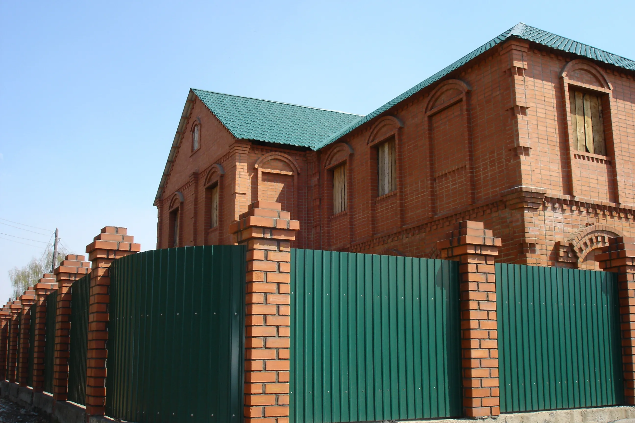 Забор из зеленого профлиста с кирпичными столбами