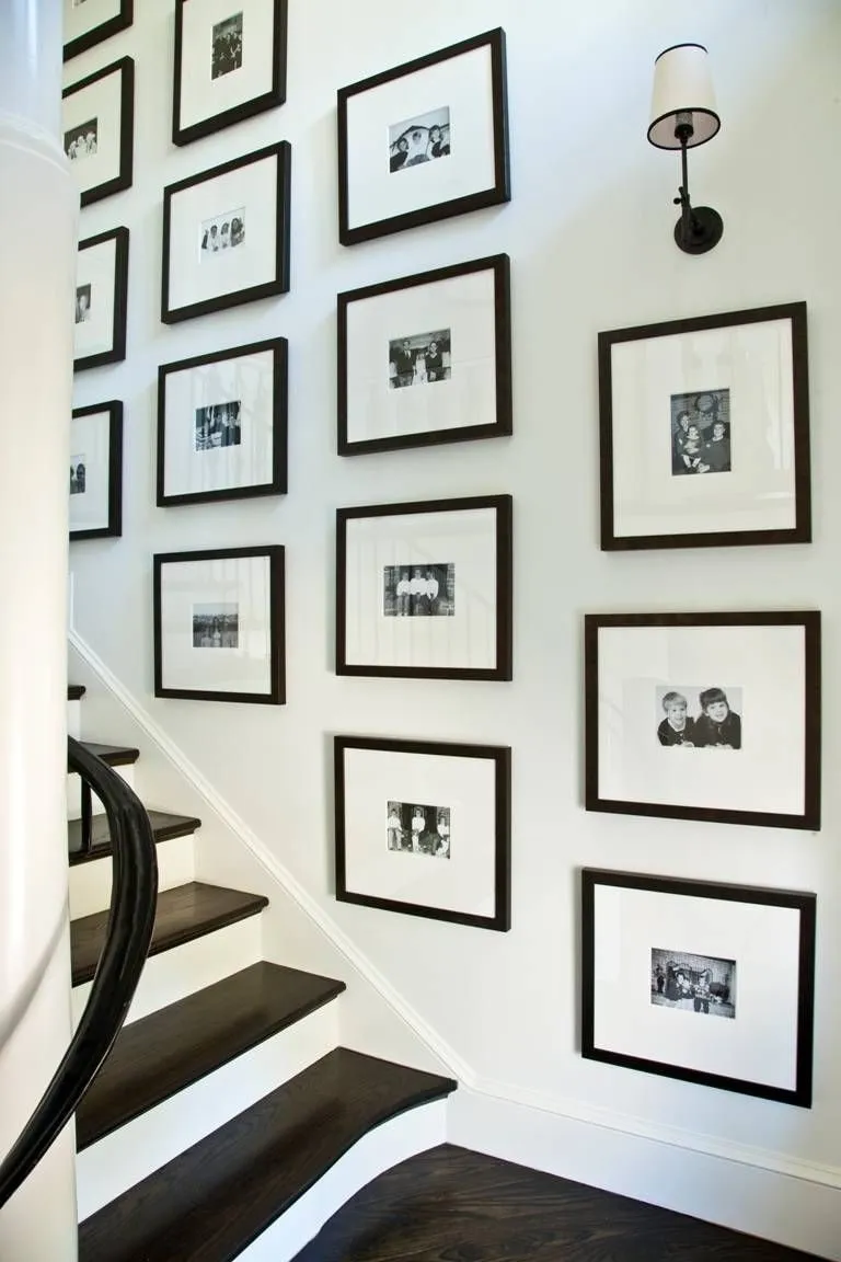 Семейные фото в одинаковых рамах на стене вдоль лестницы - отличное решение для декора частного дома